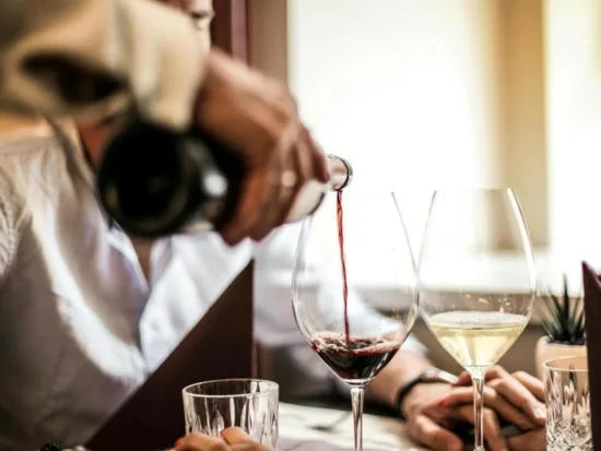 un serveur sert un verre de vin rouge après avoir servi un verre de vin blanc