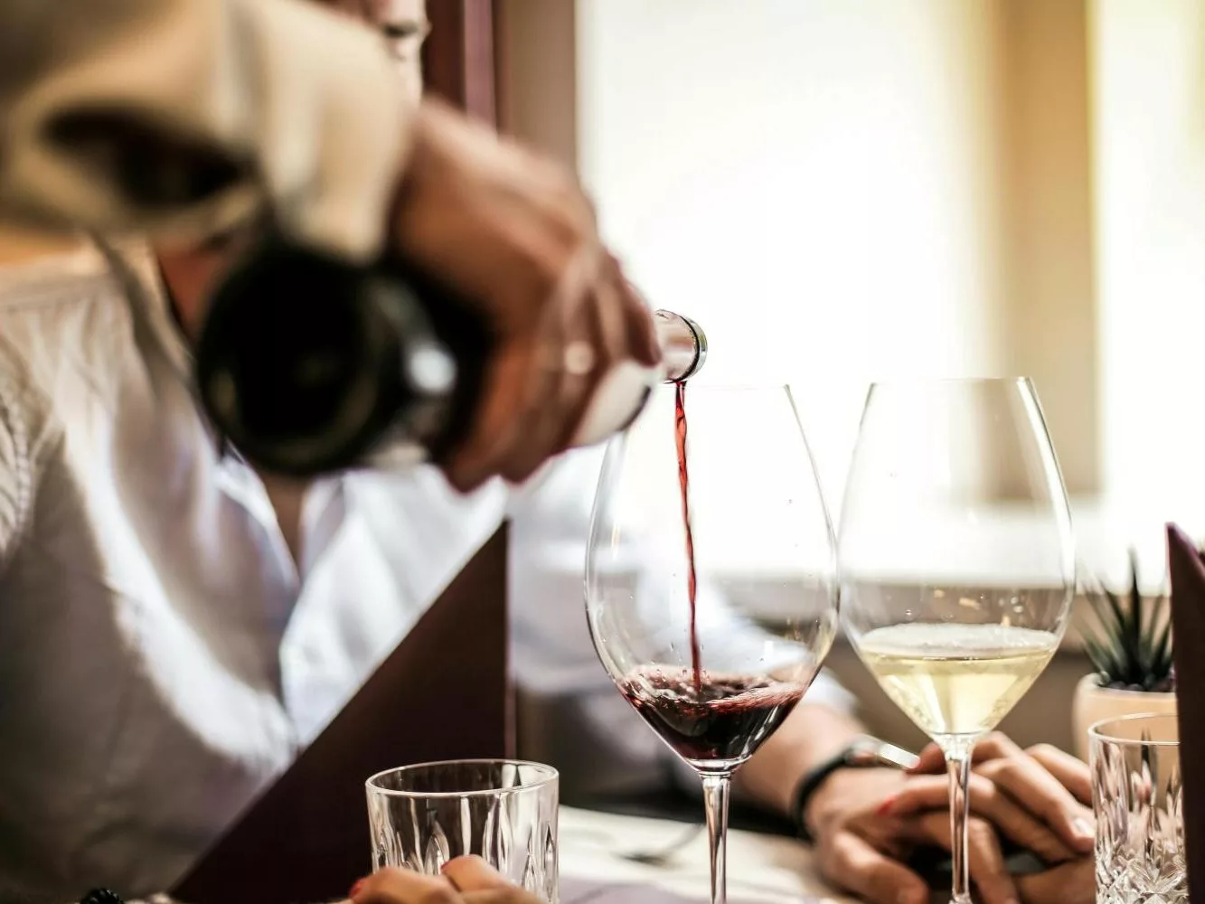un serveur sert un verre de vin rouge après avoir servi un verre de vin blanc