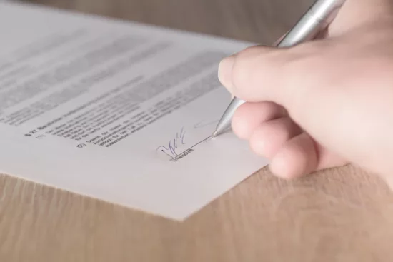 main en train de signer un contrat juridique