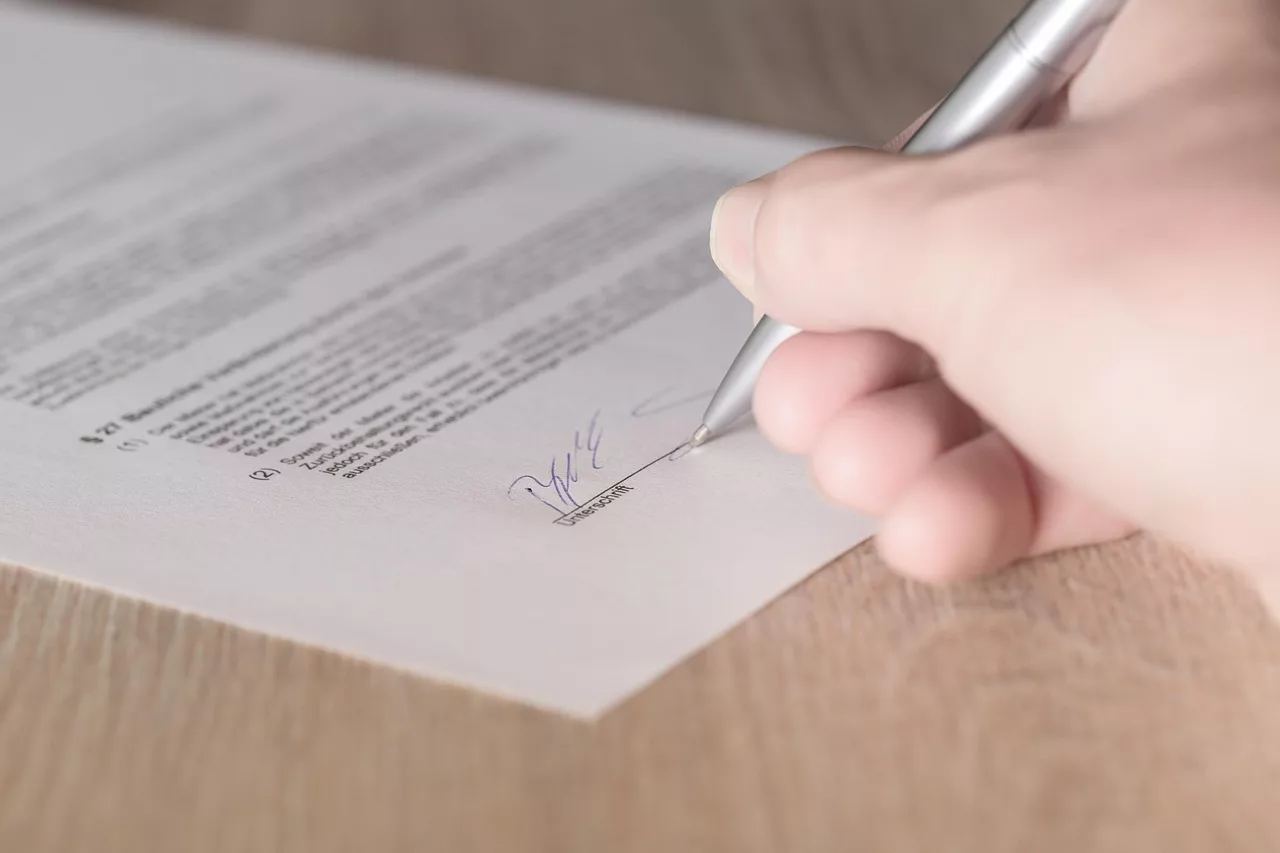 main en train de signer un contrat juridique