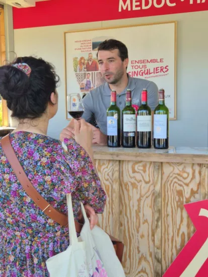 Léopold Crouzet du Château Saint-Ahon échange avec une personne visitant son stand à Bordeaux Fête le Vin, lors d'une dégustation de vin rouge
