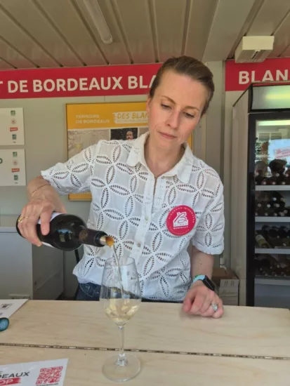Margaux Braastad Arbo des vignobles Arbo servant un verre de vin blanc sec sur son stand de Bordeaux Fête le Vin