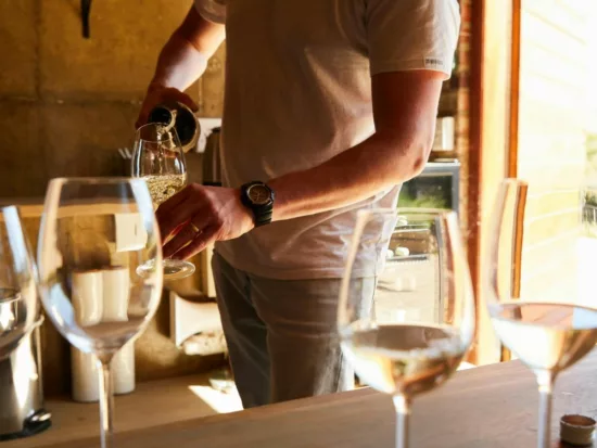 un vigneron verse un verre de vin blanc dans le cadre d'une dégustation