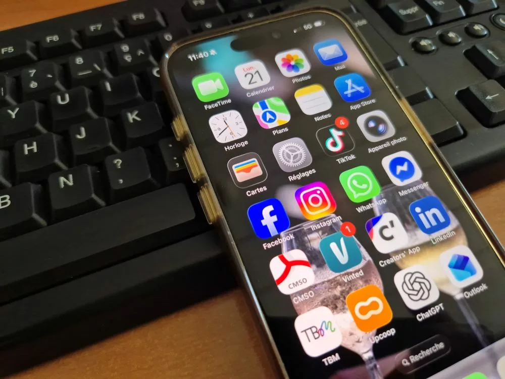 téléphone portable et ses applications de réseaux sociaux posé sur un clavier d'ordinateur